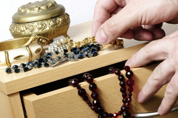 a person storing jewelry inside a wooden jewelry box