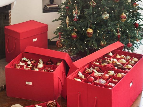 Christmas balls stored inside a red box beside a Christmas tree