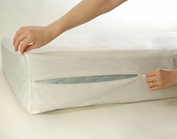A person covering a mattress with a dust cover