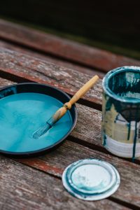 blue paint in a bowl and paint tin with a wooden paint brush