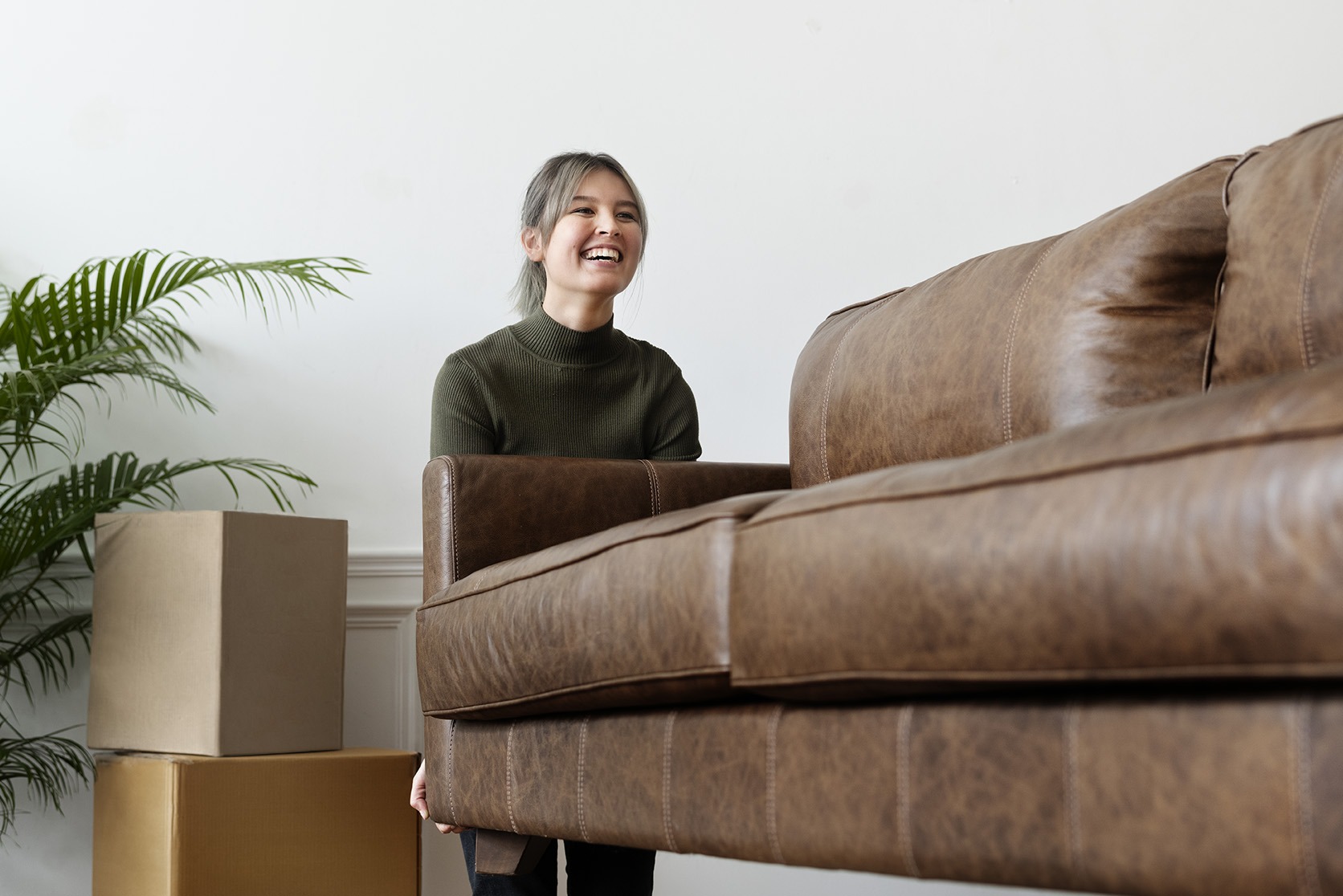 Woman moving a sofa in a new home Woman moving a sofa in a new home
